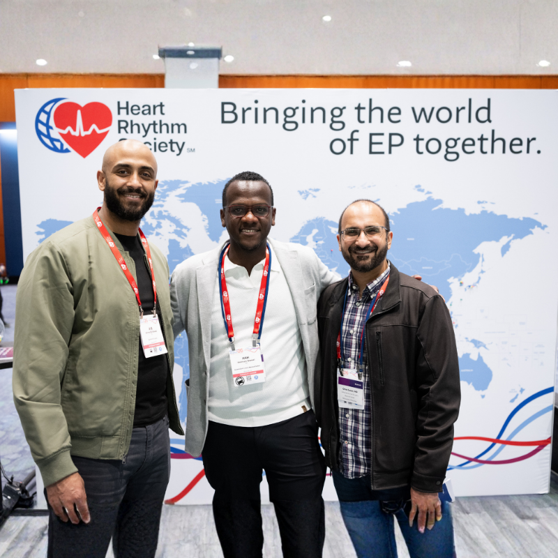 Three Heart Rhythm Society meeting attendees pose together in front of the "Bringing the world of EP together" backdrop at Heart Rhythm 2026.