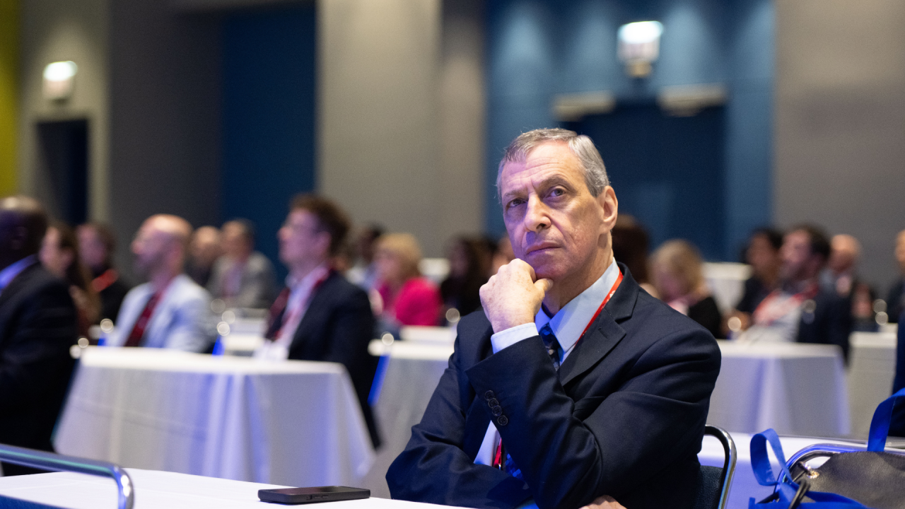 A medical professional listens attentively during a Heart Rhythm 2026 session, hand resting thoughtfully under his chin.